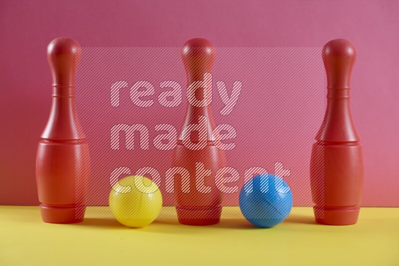 Plastic bowling pins with balls on pink and yellow background (kids toys)