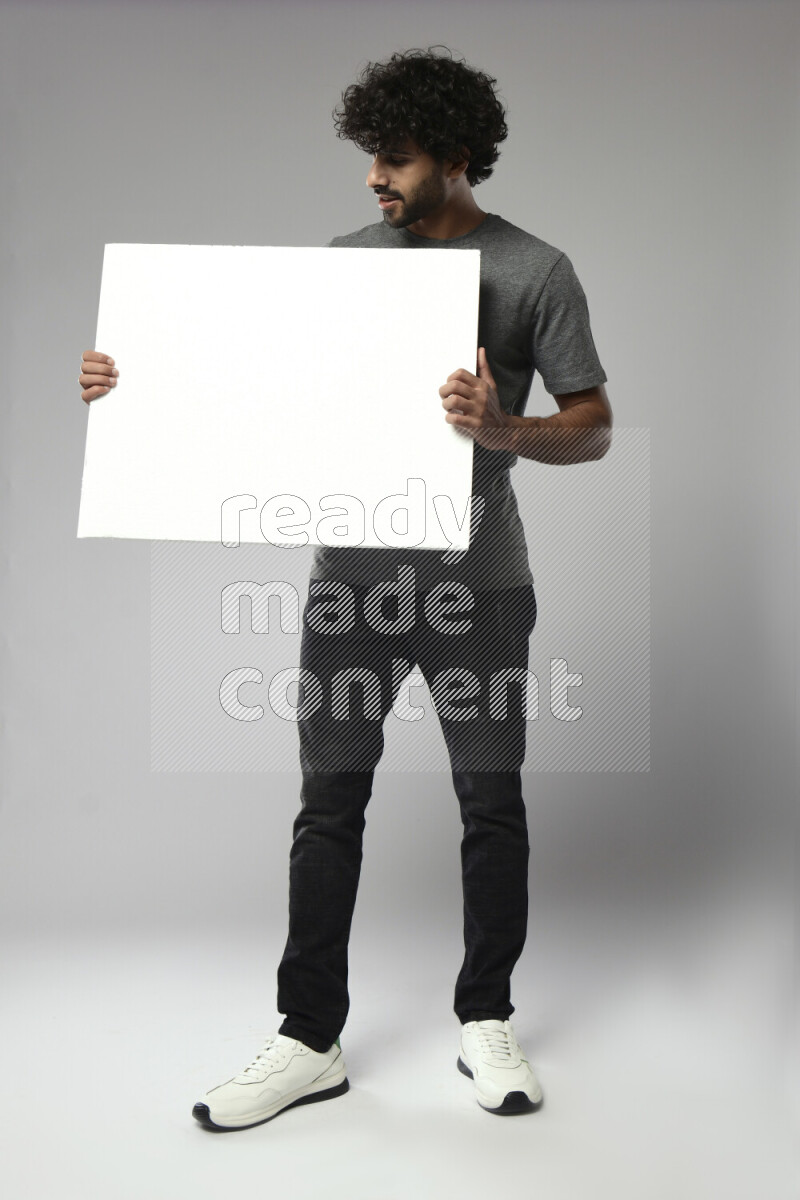 A man wearing casual standing and holding a white board on white background