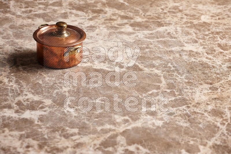 A small copper pot on beige marble background