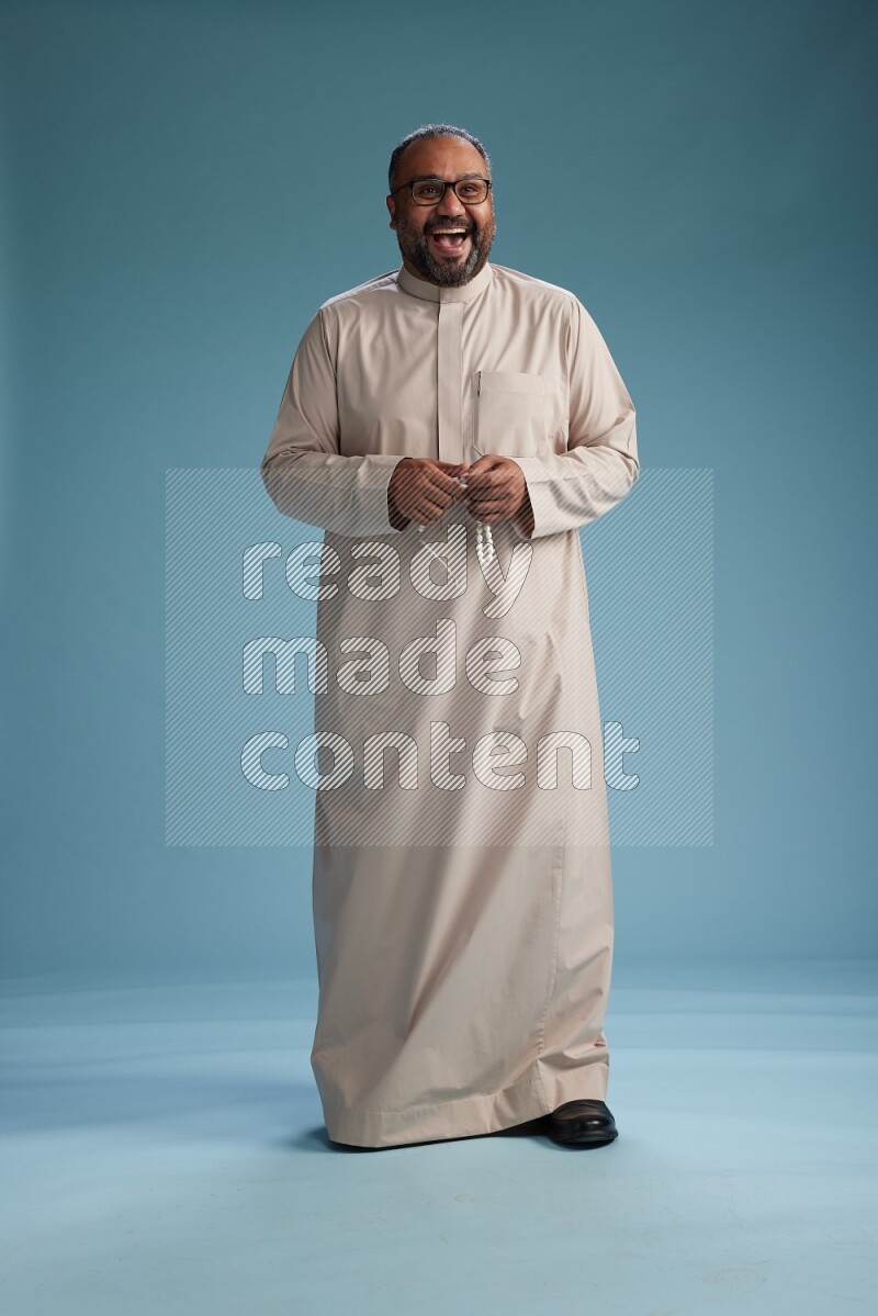 Saudi Man without shimag Standing Interacting with the camera on blue background