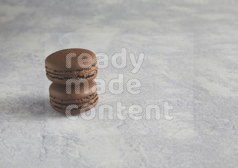 45º Shot of two Brown Dark Chocolate macarons  on white  marble background