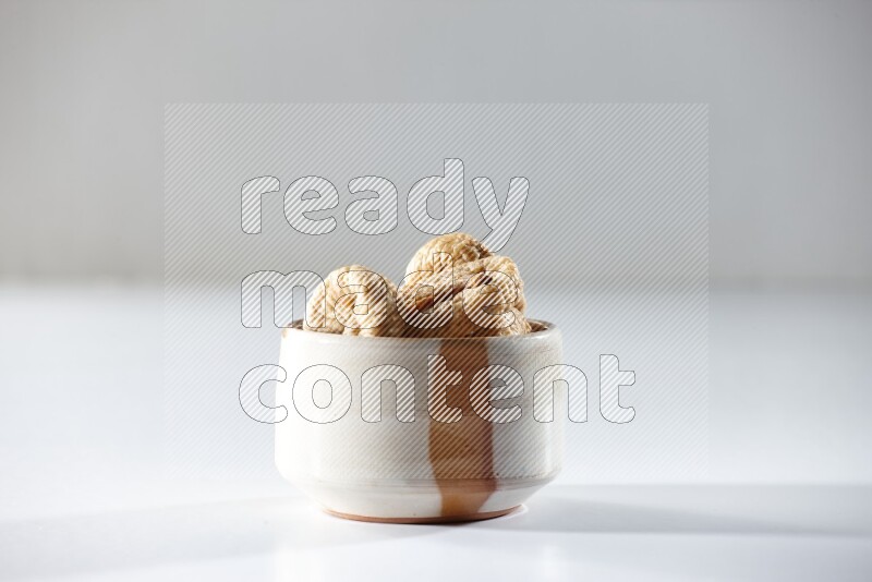 A beige ceramic bowl full of dried figs on a white background in different angles