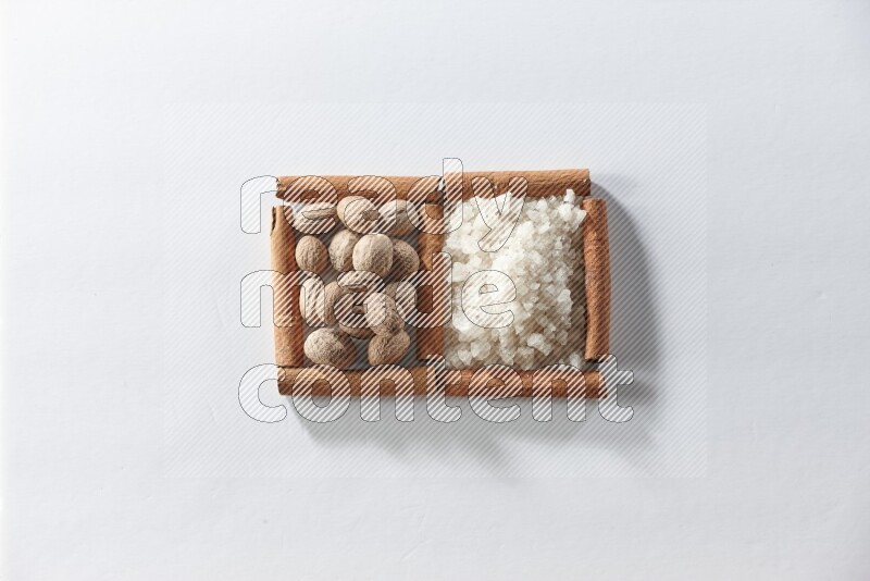 2 squares of cinnamon sticks full of white salt and nutmegs on white flooring