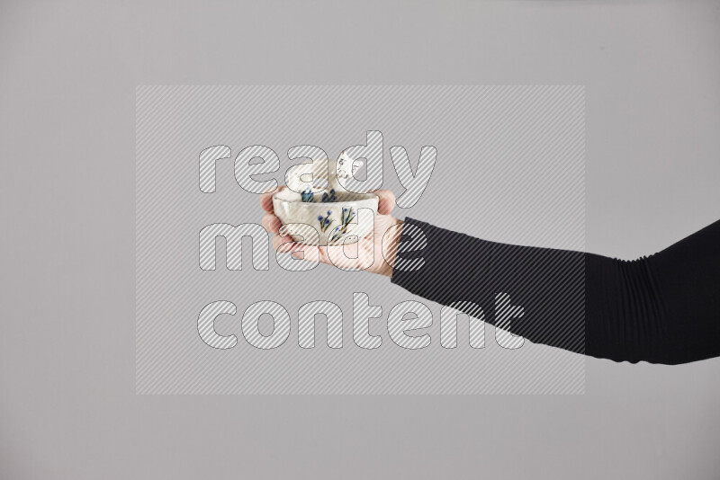 A woman in black abaya holding different pottery essentials in different positions