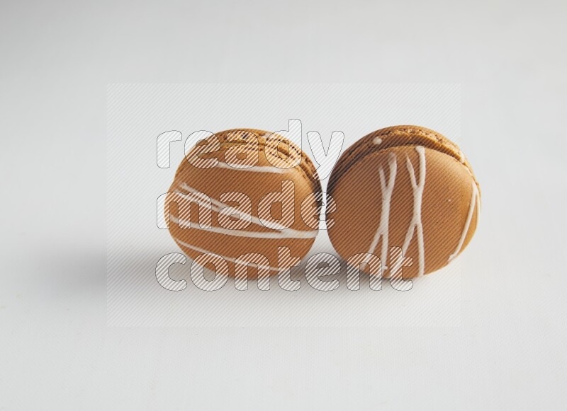 45º Shot of two Brown Irish Cream macarons on white background
