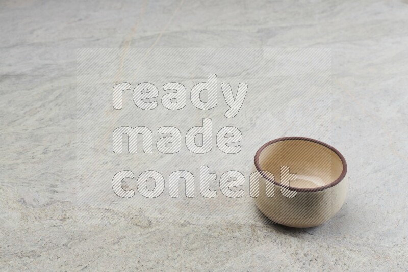 A beige pottery oven bowl on grey marble background