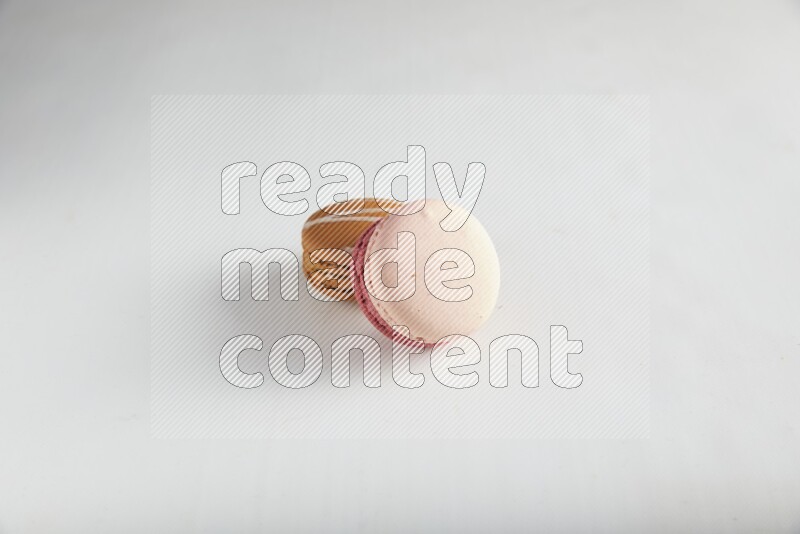 45º Shot of of two assorted Brown Irish Cream, and Pink Litchi Raspberry macarons on white background