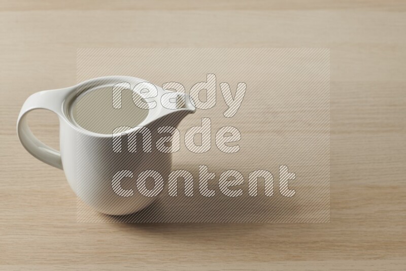 A ceramic milk jug on light wooden background