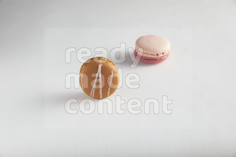45º Shot of of two assorted Brown Irish Cream, and Pink Litchi Raspberry macarons on white background