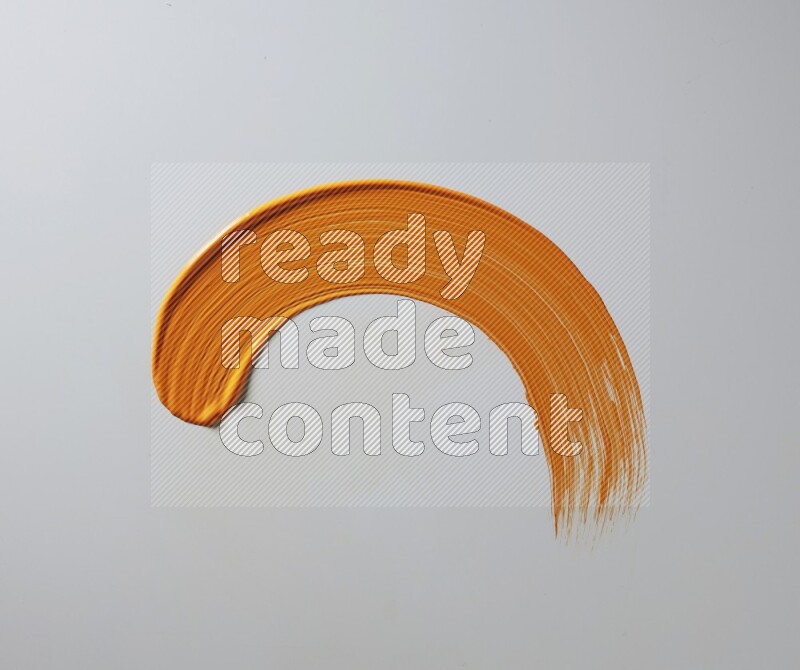 An orange half circular painting brush stroke on white background