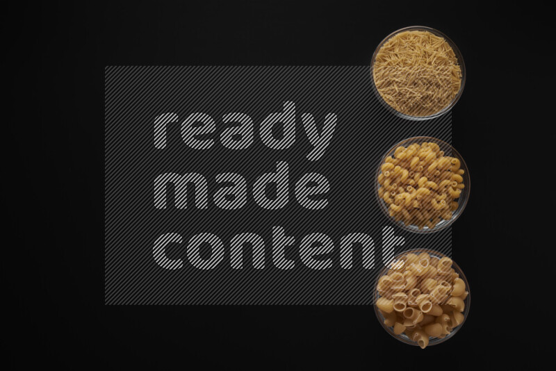 Different pasta types in 3 glass bowls on black background