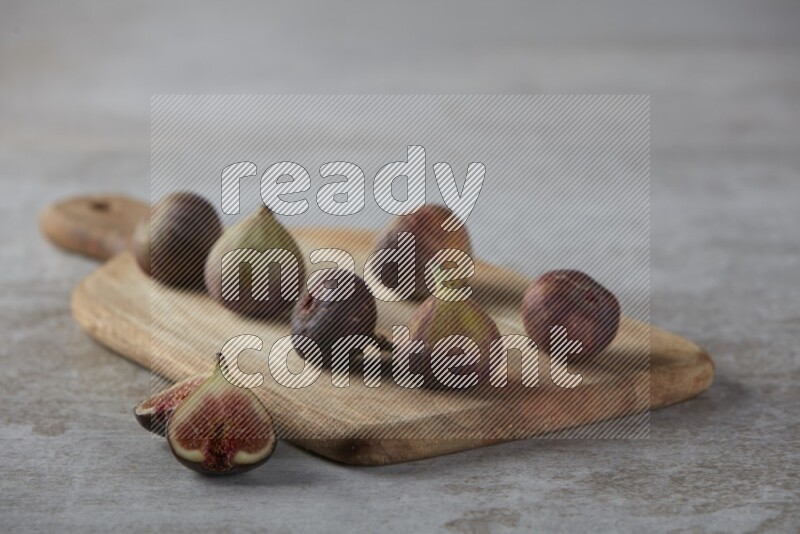 Fresh Figs on a wooden board on a textured grey background