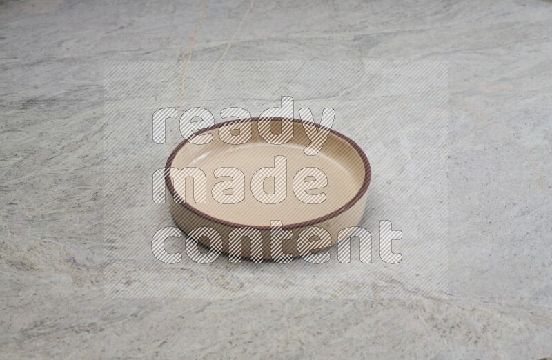 A beige pottery oven bowl on grey marble background