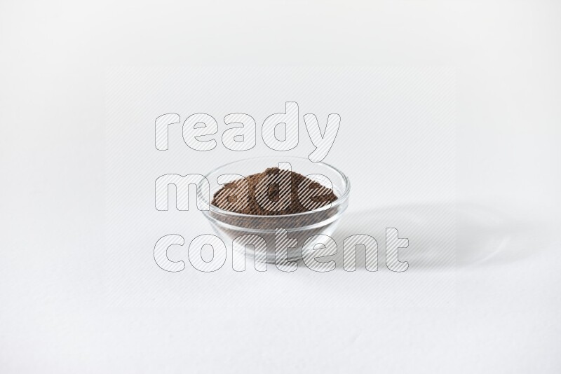 وعاء زجاجي ممتلئ ببودرة القرنفل على أرضية بيضاء