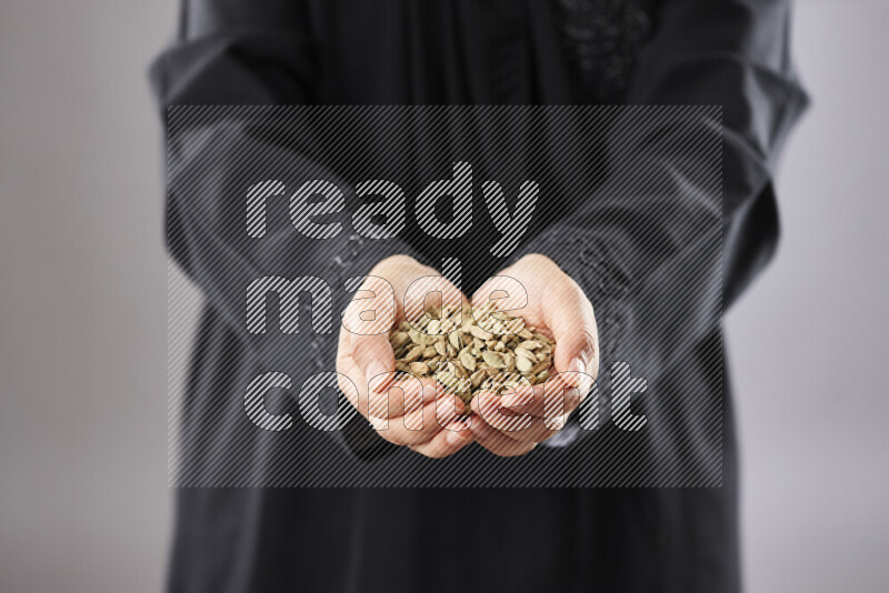 Woman in abaya holding different kinds of spices in different positions