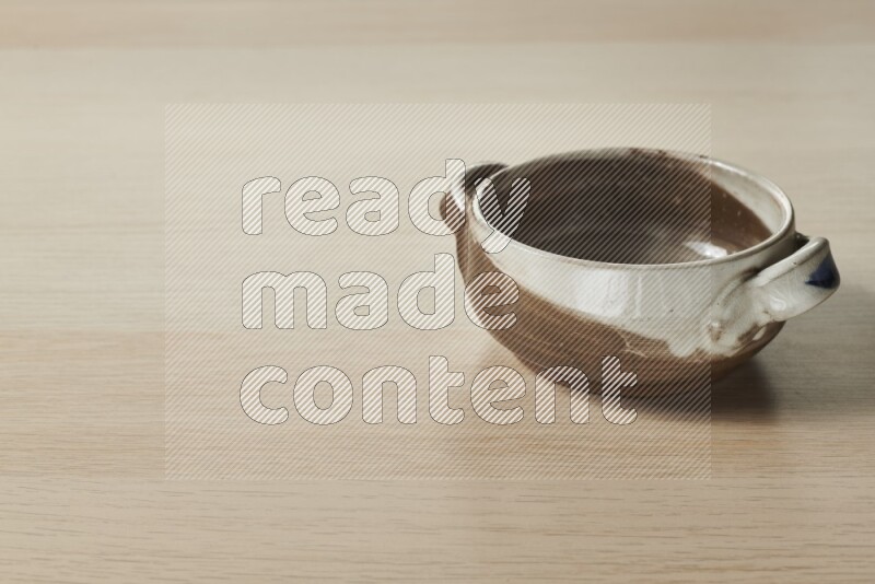 A multicolored pottery bowl on light wooden background