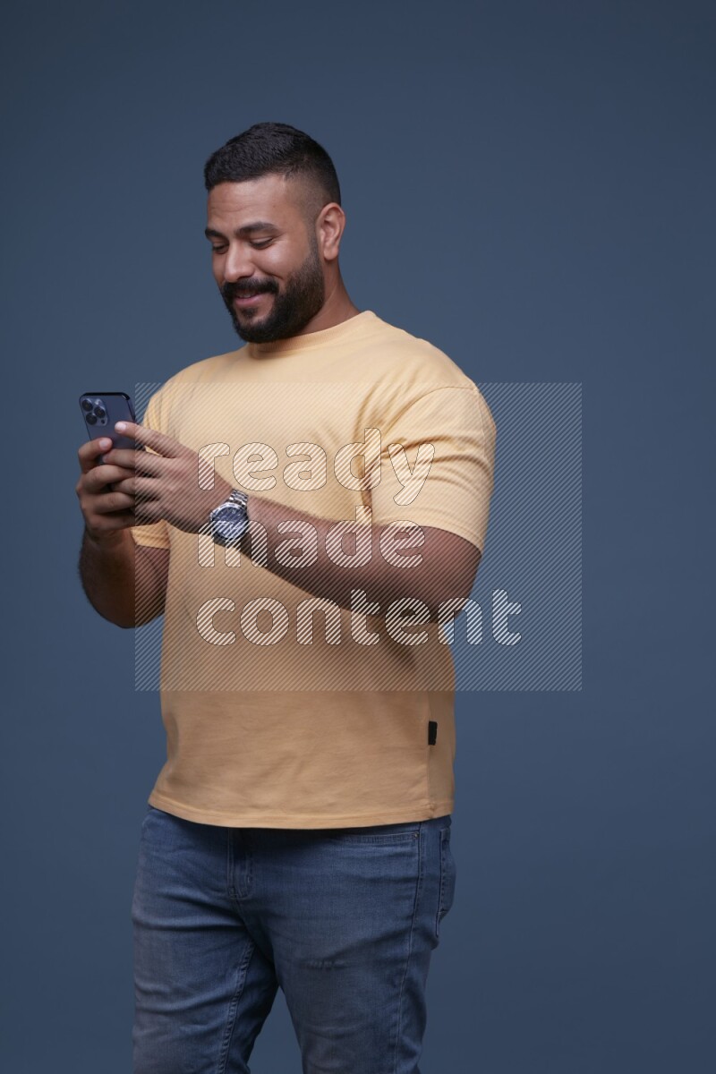 A man Texting on his phone on Blue Background wearing Orange T-shirt