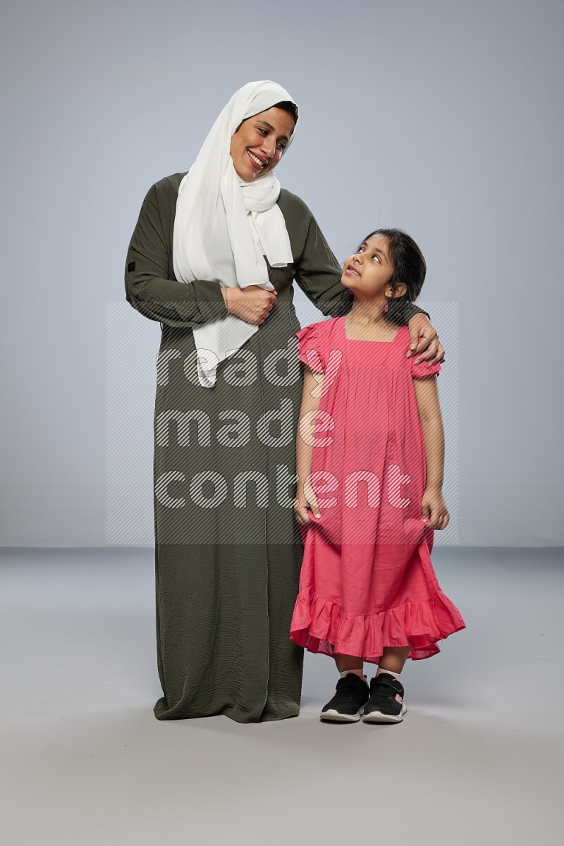 A girl and her mother interacting with the camera on gray background