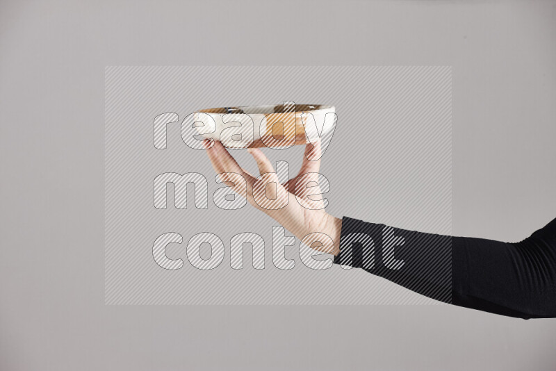 A woman in black abaya holding different pottery essentials in different positions