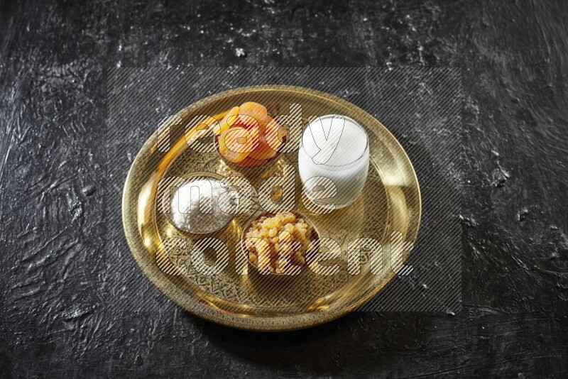 Dried fruits in metal bowls with sobya on a tray in dark setup