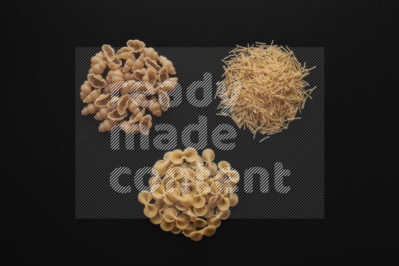 Different pasta types in bunches on black background