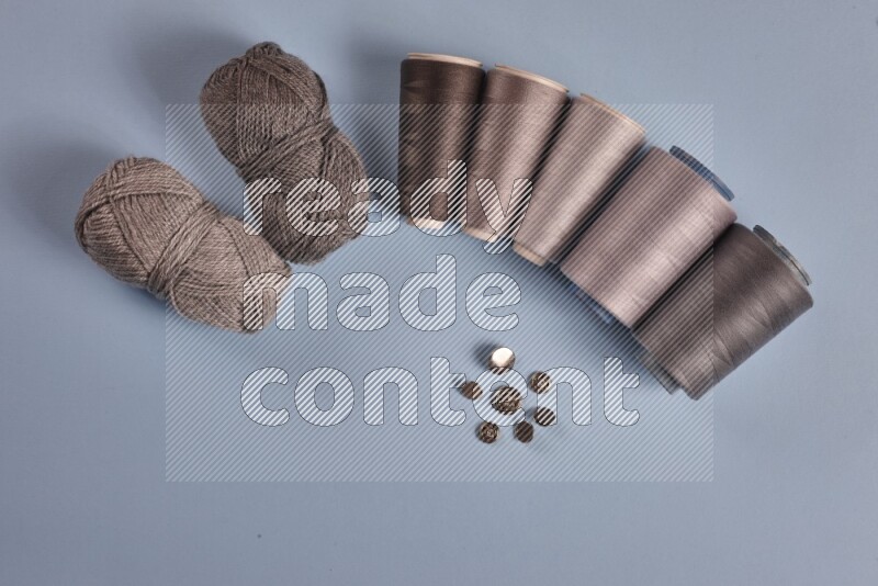 A grey collection of sewing and tailoring tools arranged on a blue background