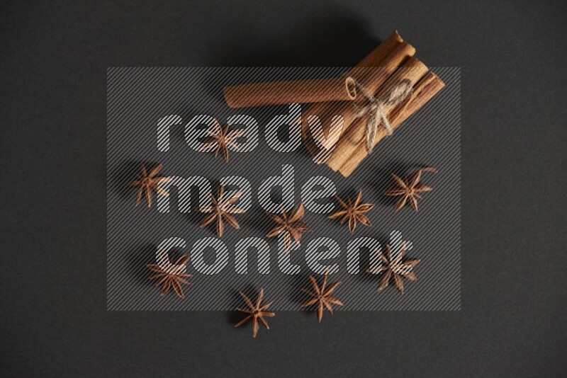 Cinnamon sticks stacked and bounded and star anise on black background