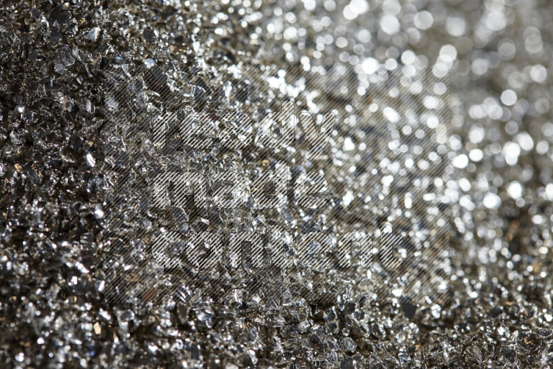 Silver shimmering fragments of glass scattered on a black background