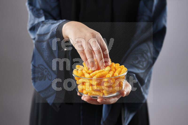 Woman in abaya holding different kinds of snacks in different positions