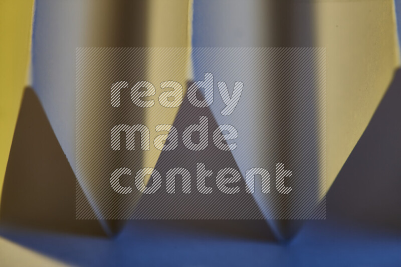 A close-up abstract image showing sharp geometric paper folds in blue gradients and warm tones