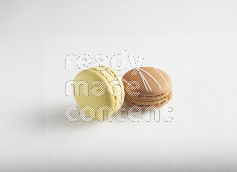 45º Shot of of two assorted Brown Irish Cream, and Yellow Lime macarons on white background