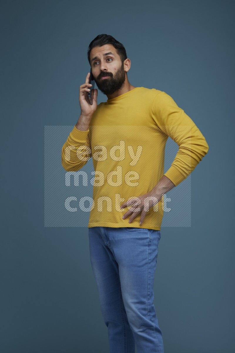 A man having a calling in a blue background wearing a yellow shirt