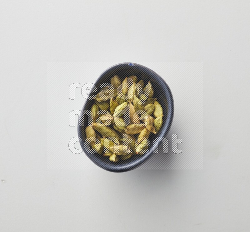 Top-view shot of Cardamon in a container on white background