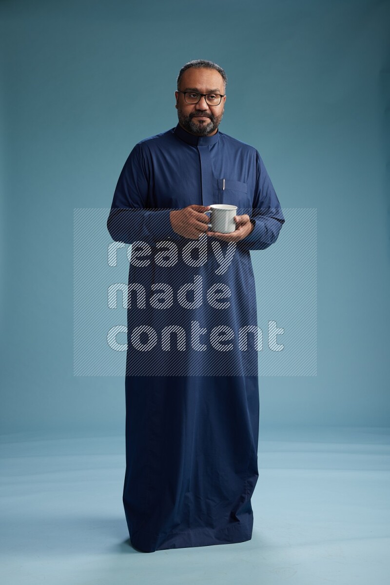 Saudi Man without shimag Standing drinking coffee on blue background