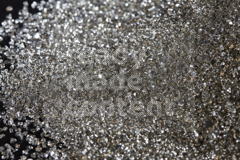 Silver shimmering fragments of glass scattered on a black background