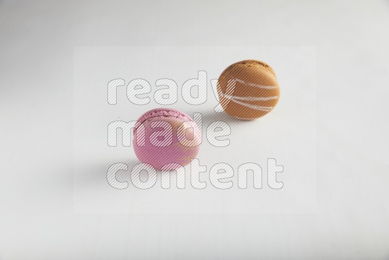 45º Shot of of two assorted Brown Irish Cream, and Purple Strawberry macarons on white background
