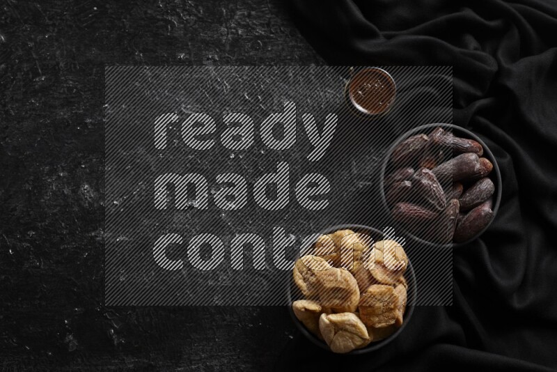 Dried fruits in pottery bowls with coffee in a dark setup