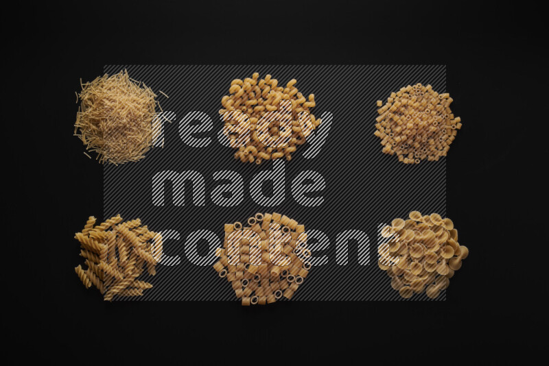 Different pasta types in bunches on black background