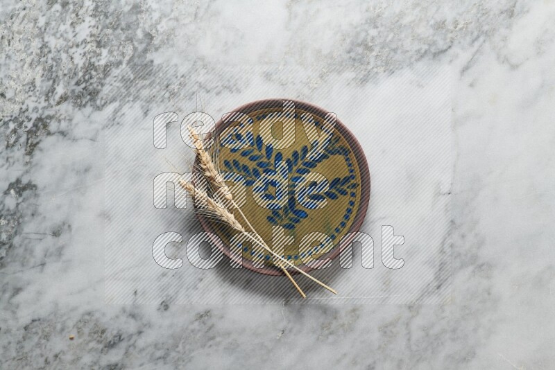 Wheat stalks on decorative pottery plate on grey marble background