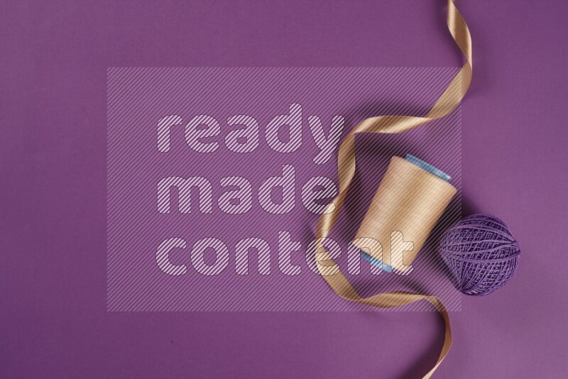 A beige collection of sewing and tailoring tools arranged on a purple background