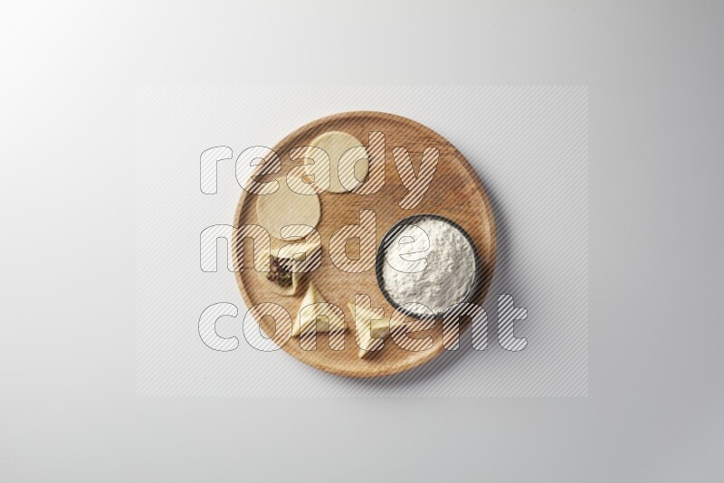two closed sambosas and one open sambosa filled with meat while flour aside in a wooden dish on a white background