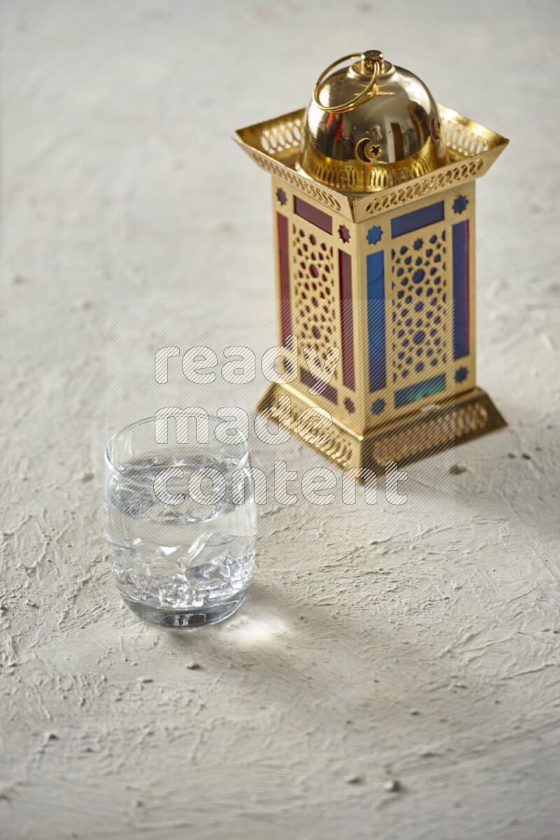 A golden lantern with different drinks, dates, nuts, prayer beads and quran on textured white background
