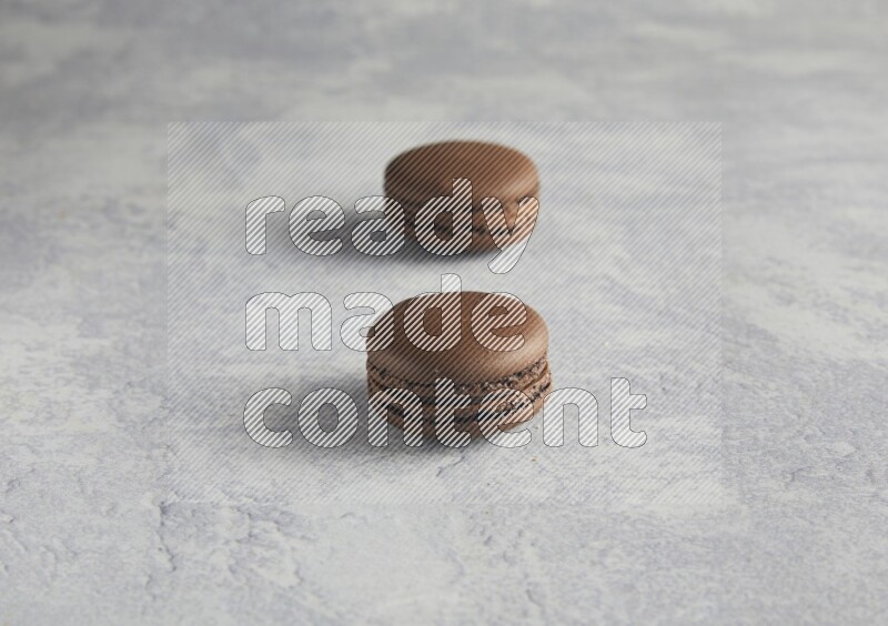 45º Shot of two Brown Dark Chocolate macarons  on white  marble background