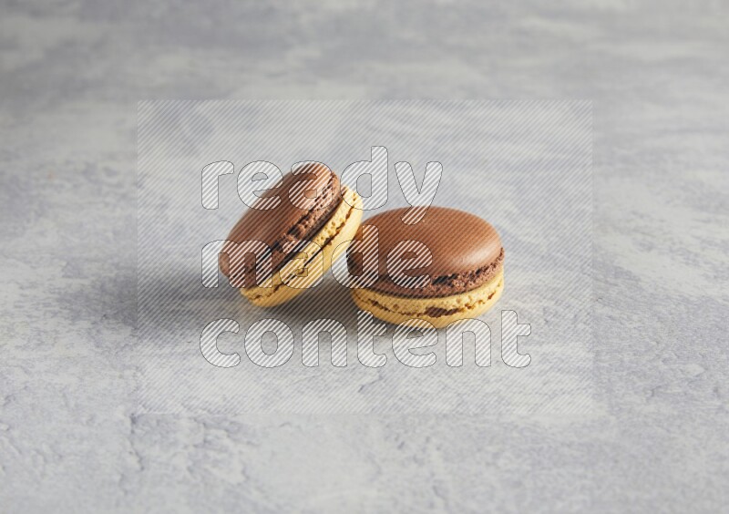 45º Shot of two Yellow and Brown Chai Latte macarons r on white  marble background