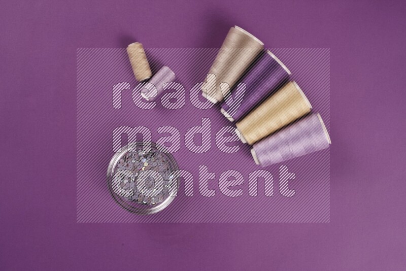 A beige collection of sewing and tailoring tools arranged on a purple background