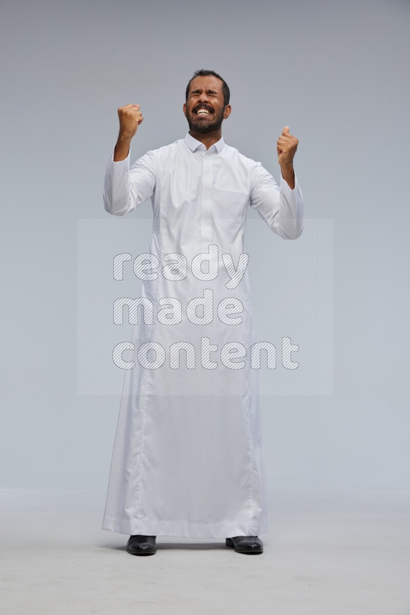 Saudi man Wearing Thob standing interacting with the camera on Gray background