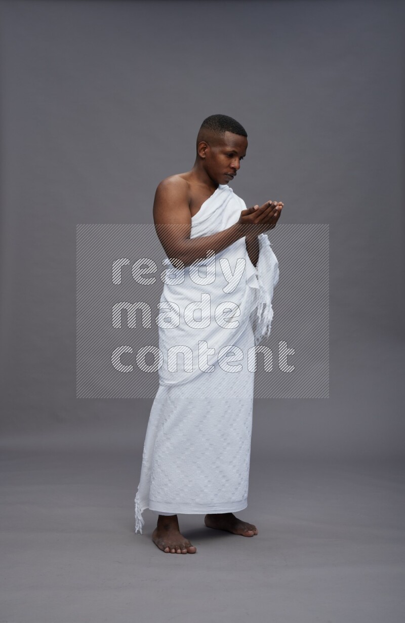A man wearing Ehram Standing dua'a on gray background