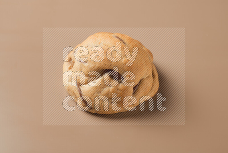 a whole chocolate chip cookie on a brown background