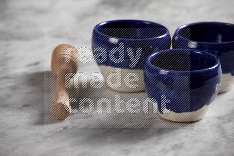 Multicolored pottery bowls with wooden honey dipper on the side on grey marble background