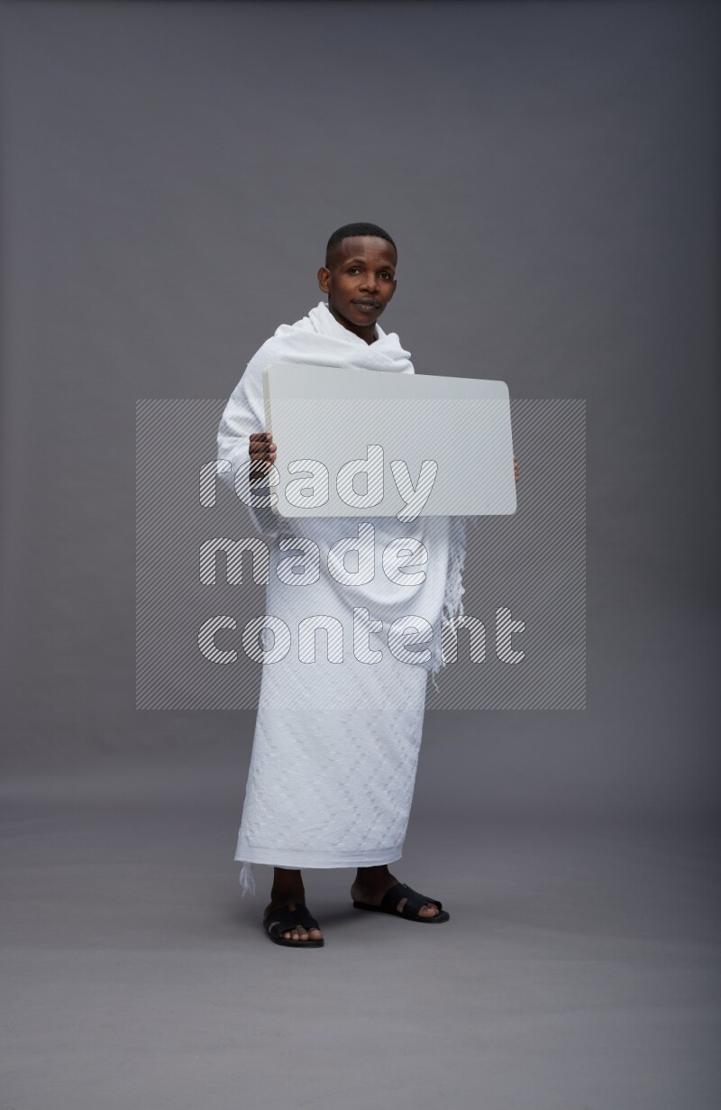 A man wearing Ehram Standing holding board sign on gray background